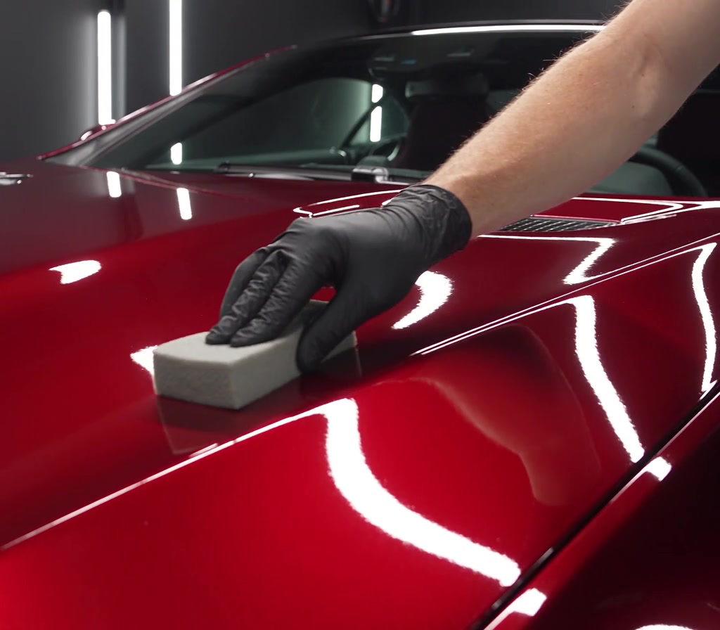 Ceramic coating applicator on glossy red paint under white studio lights